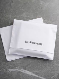 two white napkins with the word treepacking printed on them sitting on a marble surface