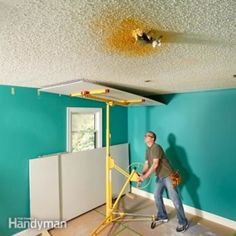 a man in a blue room painting the walls with rollers and a paint roller