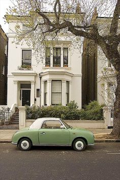 a green car parked in front of a white house