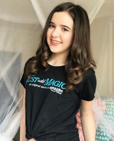 a girl with long hair wearing a black tshirt and smiling at the camera