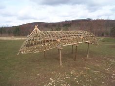 a large wooden structure sitting on top of a lush green field