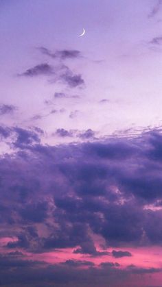 an airplane flying in the sky at dusk with a half moon above it and some clouds