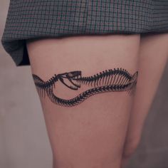 a woman's thigh with a black snake tattoo on it