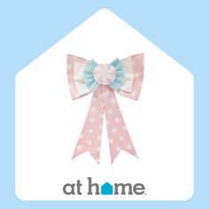 a pink and white bow with polka dots on the front, at home logo in the background