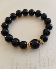 This sleek and timeless black onyx bracelet is not only a bold fashion statement but also a powerful source of protection and grounding. The smooth, polished onyx beads in a deep, jet-black tone symbolize strength and resilience, helping to ward off negative energy and bring emotional stability. Featuring delicate gold-tone accents, this bracelet adds a touch of luxury to its minimalist design, making it perfect for both casual and formal wear. Our handcrafted stone bracelets are more than just beautiful accessories--they carry the energy of nature to inspire balance, courage, and mindfulness in your daily life. Each bracelet is made with high-quality, natural stones known for their healing properties.  We believe in giving back to the community, which is why we donate every bracelet sold Emotional Stability, Increase Creativity, Black Onyx Bracelet, Handcrafted Bracelets, Onyx Bracelet, Onyx Bead, Real Stone, Negative Energy, Gemstone Bracelet