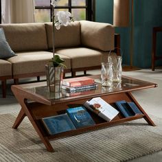 a living room with a couch, coffee table and two vases filled with flowers