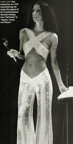 a woman in white is standing with her hands on her hip and holding a microphone