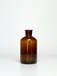 a brown glass vase sitting on top of a white table