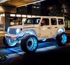 a white jeep with blue leds parked in front of a building