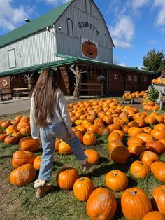 a woman walking through a field full of pumpkins