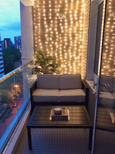 a couch sitting on top of a balcony next to a window covered in string lights