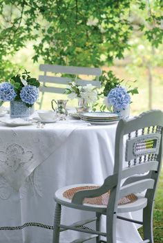 the table is set for two with blue and white flowers in vases