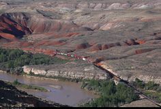 a train traveling through the mountains near a river