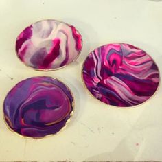 three plates sitting on top of a table covered in purple and pink swirled paint,