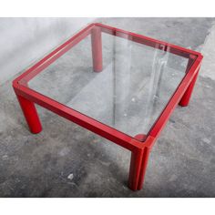 a red table with glass top on concrete floor