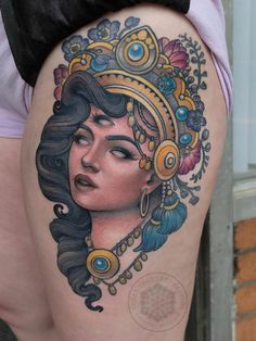 a woman's thigh with an ornate tattoo design on her leg, and headdress