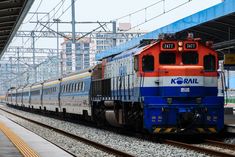 an orange and blue train pulling into a station