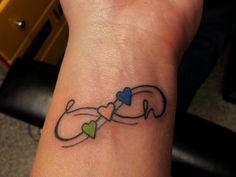 a small tattoo on the wrist of a woman's left arm with two hearts