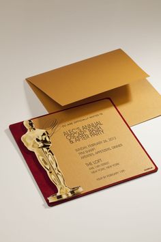 a red and gold card with an oscar statue on the front, and a golden envelope