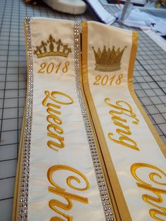 "Pageant sashes / heavyweight Cream satin/Old gold trim and thread/ Diamond Rhinestone Mesh in silver on the Queen sash/ King are Queen Crowns in Metallic Gold thread /script font / Are Diamond Rhinestone Mesh come in 18 colors The diamond Rhinestone Mesh Shines brilliantly in the light NOTE that there are no actual Rhinestones on the Product, Rather it is Made from coated Plastic indent that reflect the light very well giving the Appearance of Rhinestones , Please allow shipping time on these s Pageant Aesthetic, Royalty Theme, Pageant Sashes, Homecoming King, Miss Pageant, Prom King, Graduation Sash, Prom Themes, Custom Sash