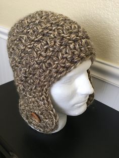 a white mannequin head wearing a crocheted hat on top of a black table