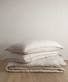 three pillows stacked on top of each other in front of a white wall and wooden floor