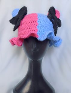 a black mannequin head with a pink and blue hat on top of it