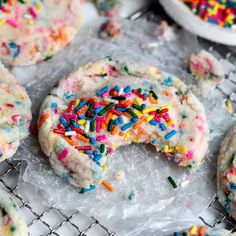 colorful sprinkles and white frosted cookies on a cooling rack