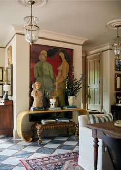 a living room filled with furniture and a painting on the wall over a coffee table