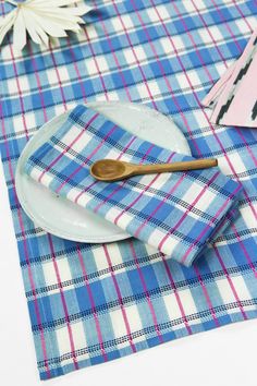 a blue and white checkered table cloth with a wooden spoon on top of it