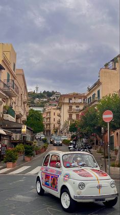 an old car is parked on the side of the road in front of some buildings