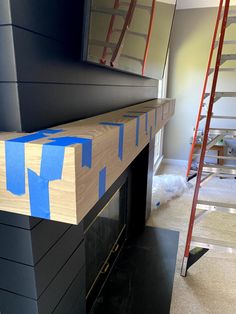 a fireplace with blue tape on it and some ladders in the room next to it