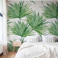 a bedroom with palm leaves painted on the wall and white bedding, along with two nightstands