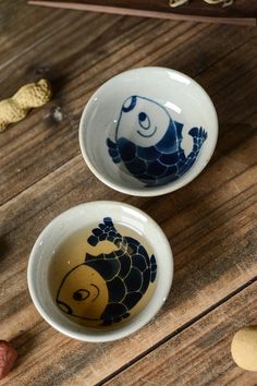 two bowls with designs on them sitting on a wooden table