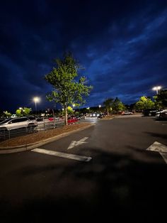 an empty parking lot at night with street lights and cars parked on the side of the road