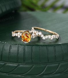 two gold rings with an orange and white topazte stone on the side, sitting on a green surface