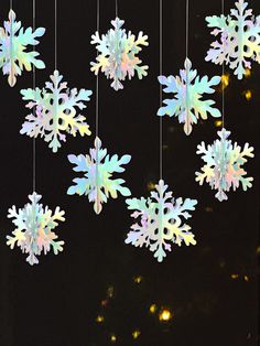 snowflakes hanging from strings in front of a black background with lights on them