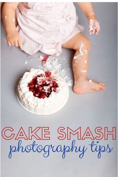 a baby sitting on the floor next to a cake with white frosting and cranberry toppings