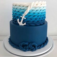 there is a blue and white cake with an anchor on the top that has braiding around it