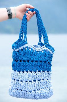 a hand holding a blue and white crocheted bag