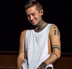 a man with tattoos on his arm is smiling and holding a knife in his hand