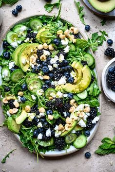 a salad with blueberries, cucumbers and avocado