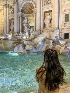 a woman standing in front of a water fountain