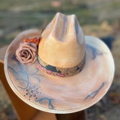 Take on the wild west in style with our Blessed Hand Painted Hat. Made from premium straw, this small-sized cowboy hat is a statement piece. Hand painted flowers and vintage details, accented with metal feathers, add a unique touch. Handmade Country Style Hat Bands For Kentucky Derby, Handmade Straw Hat For Kentucky Derby And Rodeo, Vintage Hats For Western-themed Summer Events, Handmade Straw Hat For Rodeo And Kentucky Derby, Rustic Curved Brim Straw Hat For Kentucky Derby, Western Style Felt Hat For Summer Rodeo, Handmade Fedora Straw Hat For Western-themed Events, Handmade Hat Bands For Kentucky Derby, Handmade Hat Bands For Ranch In Spring