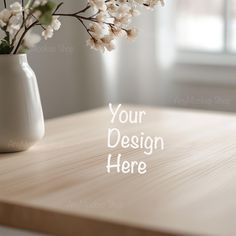 a vase with flowers on a wooden table in front of a window that says your design here