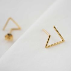 "Delicate triangle studs inspired by geometry and clean lines. These minimalist easy-to-wear earrings are simple but elegant, perfect choice to add a unique touch to your casual look. The pair of earrings is carefully handcrafted by us from a 1mm wire. Available in sterling silver or 22K yellow gold fill over sterling silver (5 micrometers of gold) both in shiny polished finish. Post of 19 gauge wire // 1mm diameter This listing is for one pair of earrings including ear backs. ------ HIGH QUALIT Gold Triangle Minimalist Earrings, Minimalist Gold Triangle Earrings, Minimalist Triangle Earrings For Everyday, Triangle Studs, Minimalist Studs, Earrings Minimalist, Geometric Earrings, Recycled Sterling Silver, Gold Plated Silver