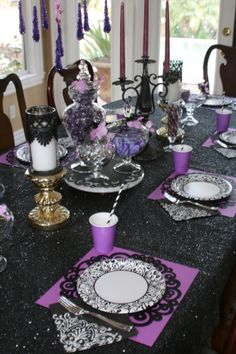 the table is set with purple and black place settings