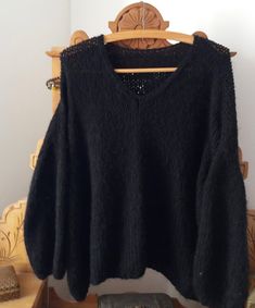 a black sweater hanging on a wooden rack