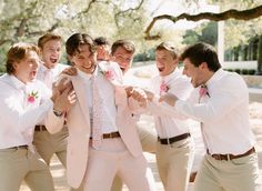 a group of young men standing next to each other in front of a tree with their mouths open