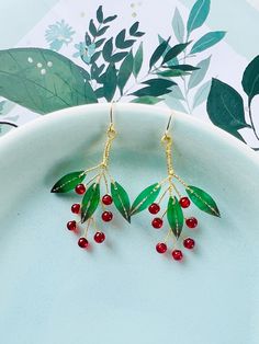 Celebrate the festive spirit with these charming Shrink Plastic Green Leaves with Red Berries Dangled Drop Earrings, a handmade creation that captures the essence of the holiday season. These earrings are a delightful expression of creativity and craftsmanship, blending the lush greenery of leaves with the cheerful vibrancy of red berries. Each earring features intricately designed green leaves, meticulously crafted from shrink plastic to capture the intricate details and rich hues of nature's f Handmade Earrings For Holiday Celebrations, Handmade Earrings For Celebrations And Holidays, Holiday Handmade Earrings For Celebration, Handmade Earrings For Valentine's Day Celebration, Elegant Green Holiday Earrings, Red Drop Earrings For Holiday, Red Dangle Earrings For Christmas, Dangle Earrings As Holiday Gifts, Red Festive Earrings For New Year